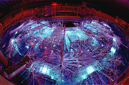 The Z machine at Sandia National Laboratory. Due to the extremely high voltage, the power feeding equipment is submerged in concentric chambers of 2 megalitres (2,000 m?) of transformer oil and 2.3 megalitres (2,300 m?) of deionized water, which act as insulators. Nevertheless, the electromagnetic pulse when the machine is discharged causes impressive lightning, referred to as "arcs and sparks" or "flashover", which can be seen around many of the metallic objects in the room. Courtesy, Sandia National Laboratories